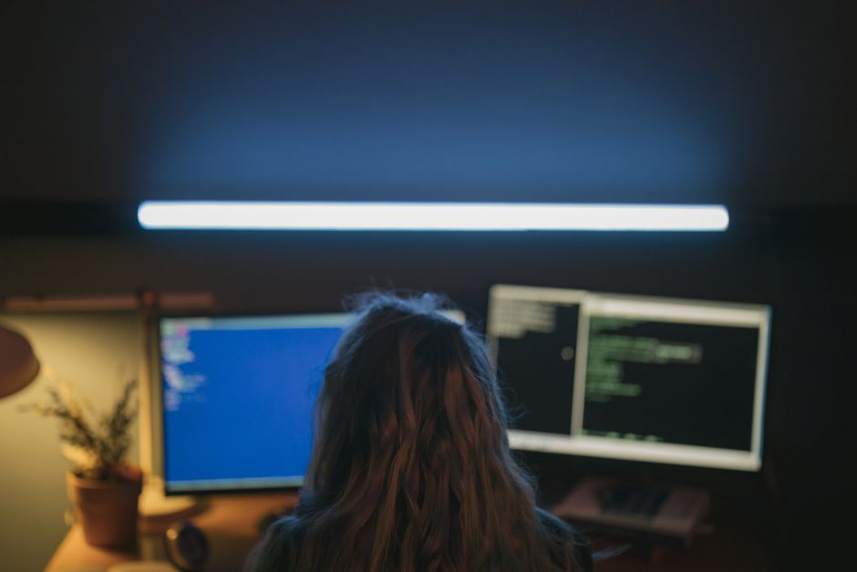 Softverski razvojni inženjer radi u prostoriji s dva osvijetljena monitora prikazana kôd