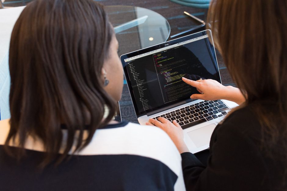 Dvije programerke zajedno rade na razvoju softvera i prate kôd na ekranu