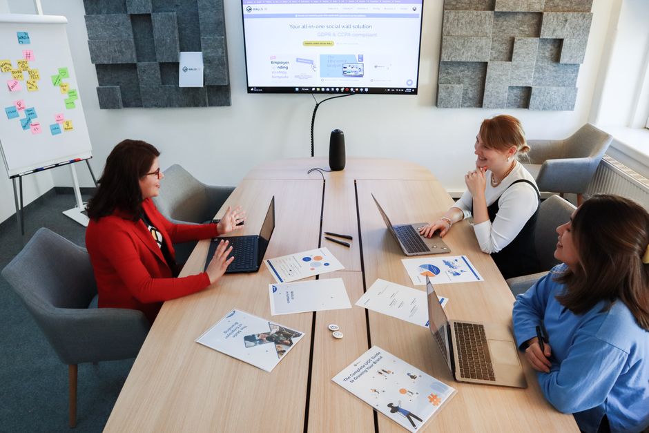 Tri žene zajedno rade na laptopima za konferencijskim stolom u modernom uredu